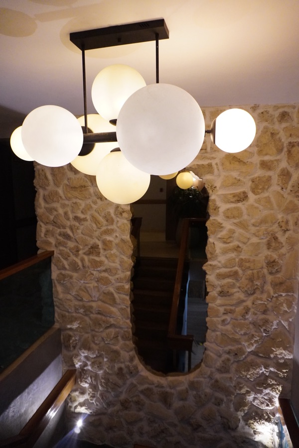 Staircase with a stone wall, an oval mirror and a globe lamp