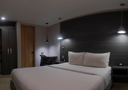 Standard room without a window, with a double bed and a grey wall